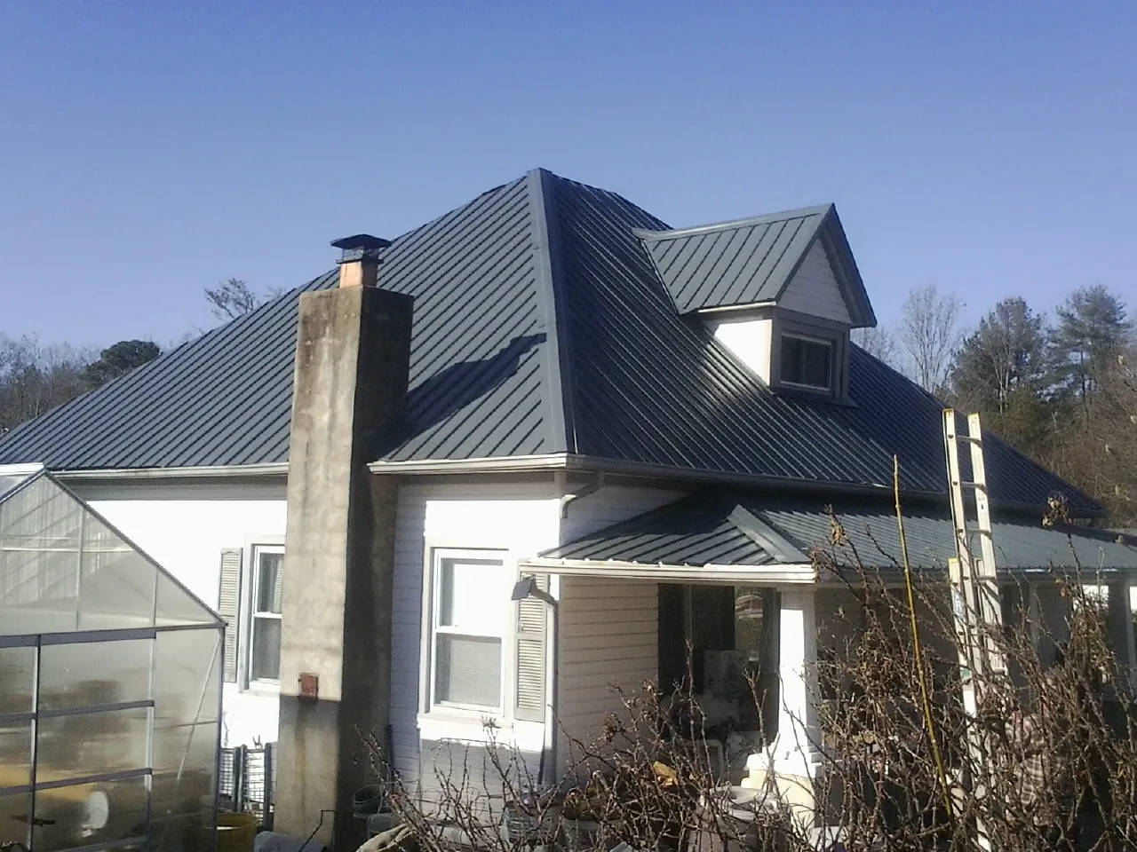 Dark blue standing seam metal roof on a white farmhouse with dormer — Slate & Tile Roof Repair by Roofing Brothers in Dandridge
