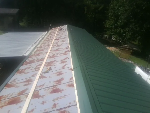 Old rusted panels beside newly installed green metal roofing — Wind Damage Roof Repair by Roofing Brothers in Dandridge