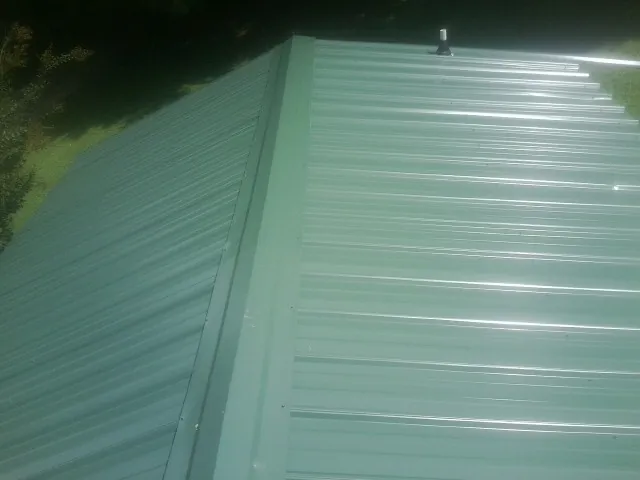 New green metal panels meeting at the ridge of a roof — Flat Roof Repair work by our crew in Dandridge