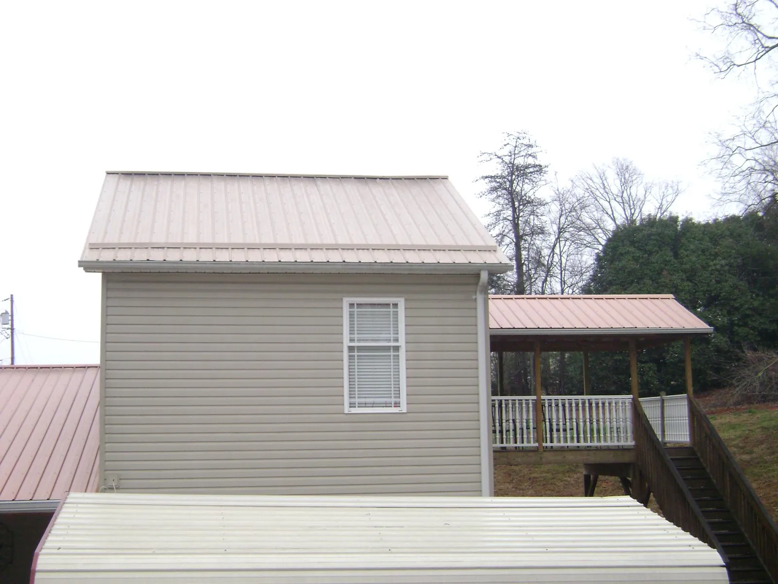 Tan metal roofs on a two story addition and attached porch, from a Roof Replacement job in Dandridge