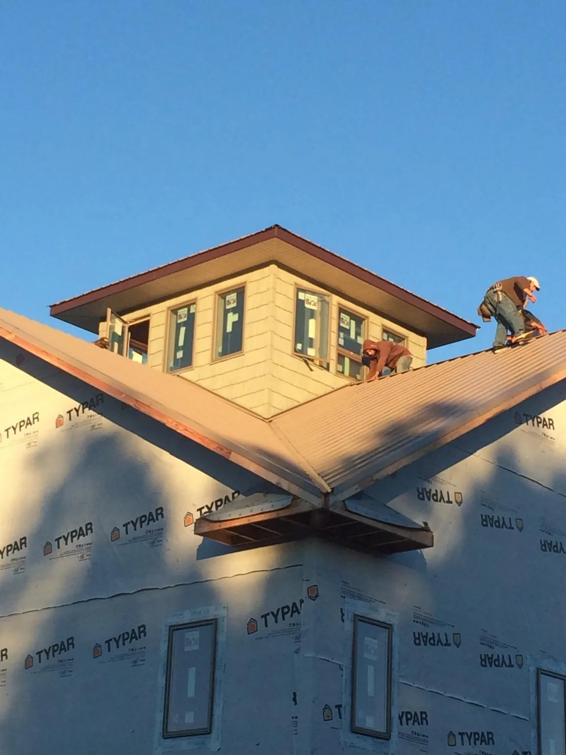 Roofers working around a rooftop cupola on a new metal roof at sunset — Roof Waterproofing in Dandridge by Roofing Brothers